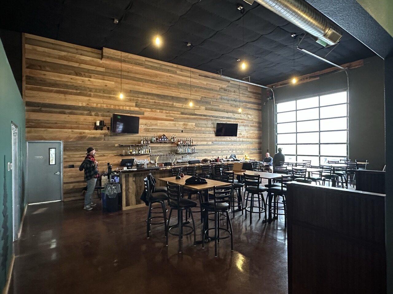 Battery 245 taproom bar with reclaimed wood wall and roll-up garage door